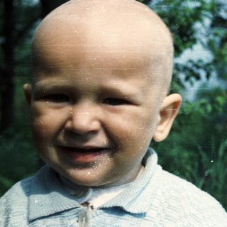 Infant with a bright smile in an outdoor setting.