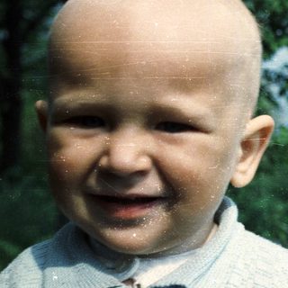 Infant with a bright smile in an outdoor setting.