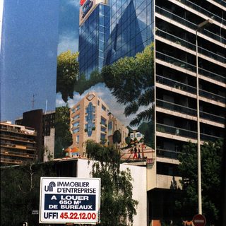 Modern building with signage, palm trees, and a rental advertisement.