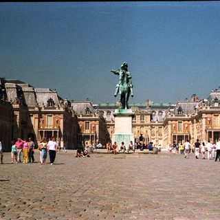 Palace of Versailles courtyard with statue and people.