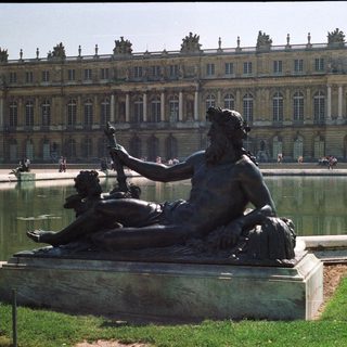 Bronze statue overlooking a fountain at Versailles palace.