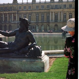 Bronze statue overlooking a fountain at Versailles palace.