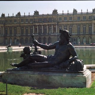 Bronze statue overlooking a fountain at Versailles palace.
