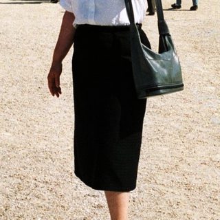 Woman stands in front of the Palace of Versailles.