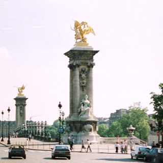 Parisian avenue with monuments, traffic, and a distant dome.