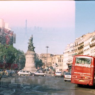 Parisian street scene with a red double-decker bus and statue.