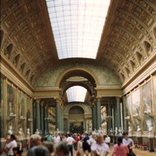 Here's a brief summary of the image: Large museum hall with people viewing artwork and architecture.