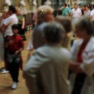 Here's a brief summary of the image: Large museum hall with people viewing artwork and architecture.