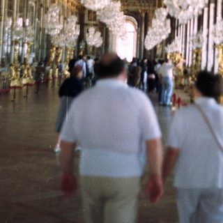 Opulent hall with crystal chandeliers and tourists.