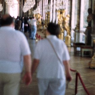 Opulent hall with crystal chandeliers and tourists.