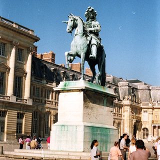 Monumental equestrian statue stands in front of a palace.