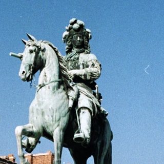 Monumental equestrian statue stands in front of a palace.