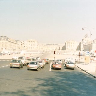 Paris street scene with buildings, cars, and a hazy sky.