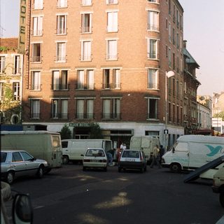 Hotel facade with street parking and vehicles visible.