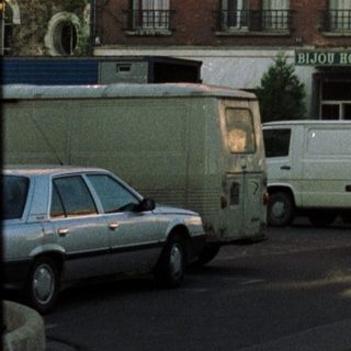 Hotel facade with street parking and vehicles visible.