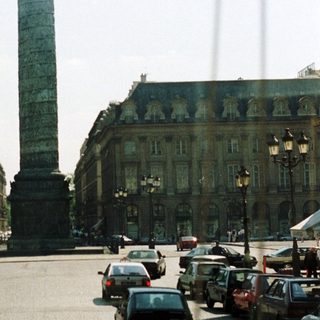 Parisian square with a tall monument and buildings.