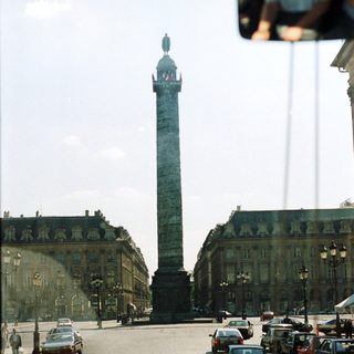 Parisian square with a tall monument and buildings.