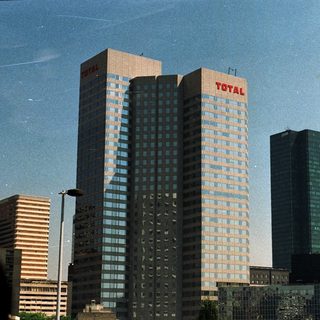 Skyscrapers featuring "Total" signage dominate a city skyline.