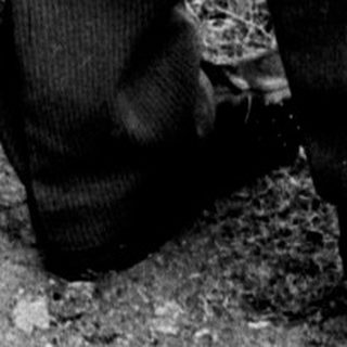 Man and woman standing near a gravesite, looking down.
