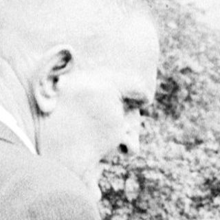 Man and woman standing near a gravesite, looking down.