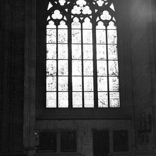 Black and white image of a large, ornate stained glass window.