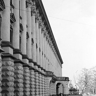 Classical building facade with cars on a cobblestone street.