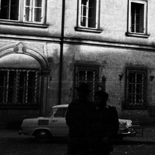 Black and white photo depicts old buildings and cars.