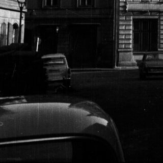 Black and white photo of an ornate building with cars.