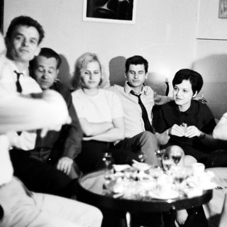 Group of people sitting, gathered around a table.