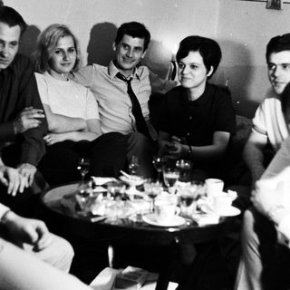Group of people socializing in a room with a table.