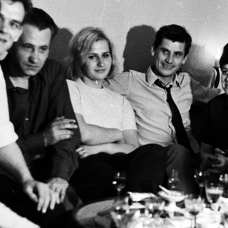Group of people socializing in a room with a table.