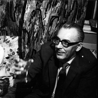 Couple seated on a sofa, smiling in a black and white photo.