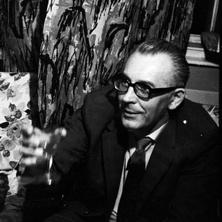 Couple seated on a sofa, smiling in a black and white photo.