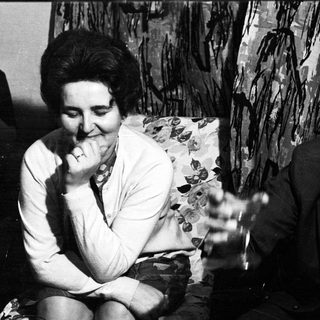 Couple seated on a sofa, smiling in a black and white photo.
