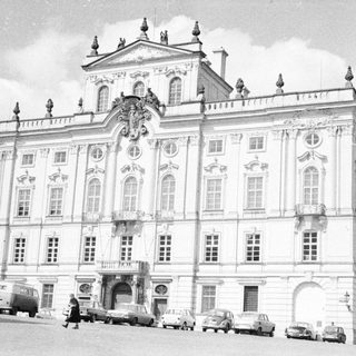 Elegant, historic building with vintage cars in a public square.