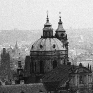 Black and white cityscape with church spires and rooftops.