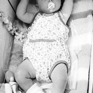 Baby in a crib, holding a pacifier.