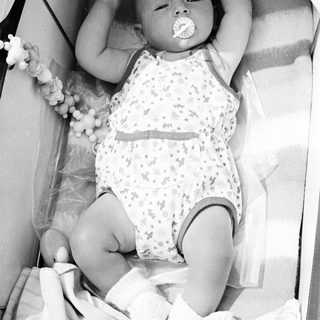 Baby in a crib, holding a pacifier.