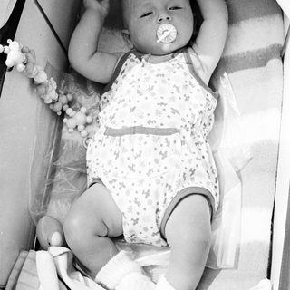 Baby in a crib, holding a pacifier.