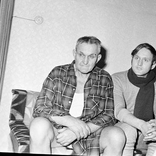Here's a brief summary of the image: Three people sit indoors, appearing to be a family.