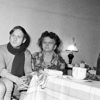 Here's a brief summary of the image: Three people sit indoors, appearing to be a family.