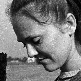 Young woman outdoors, holding something, looking down.