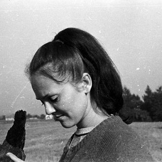 Young woman outdoors, holding something, looking down.