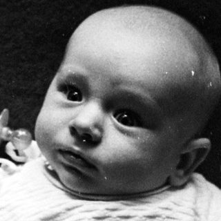 Black and white photo of an infant lying on a blanket.