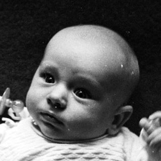 Black and white photo of an infant lying on a blanket.