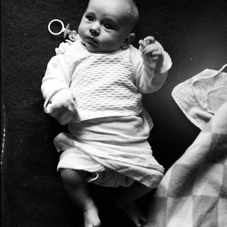 Black and white photo of an infant lying on a blanket.