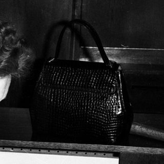 Woman smoking near a table with vintage items.