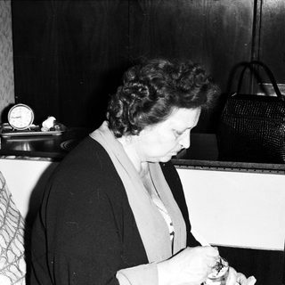 Woman smoking near a table with vintage items.