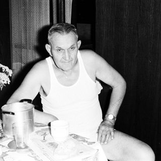 Man seated at a table with eggs and a vase.