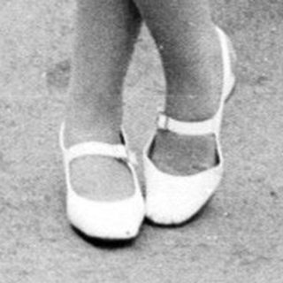 Woman with vintage pram walking on a paved road.
